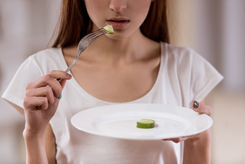 woman with eating disorder eating small portion of vegetables