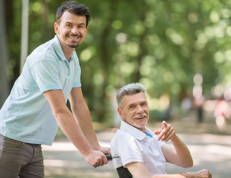 male caregiver pushing older man in wheelchair