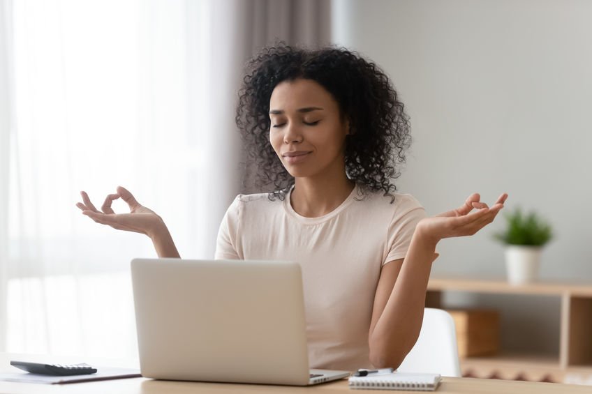 woman meditating while working from home to cope with anxiety