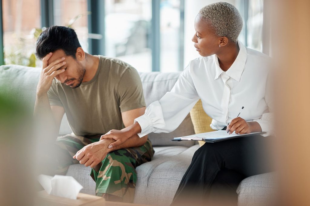 therapist and man in military uniform discussing ptsd symptoms