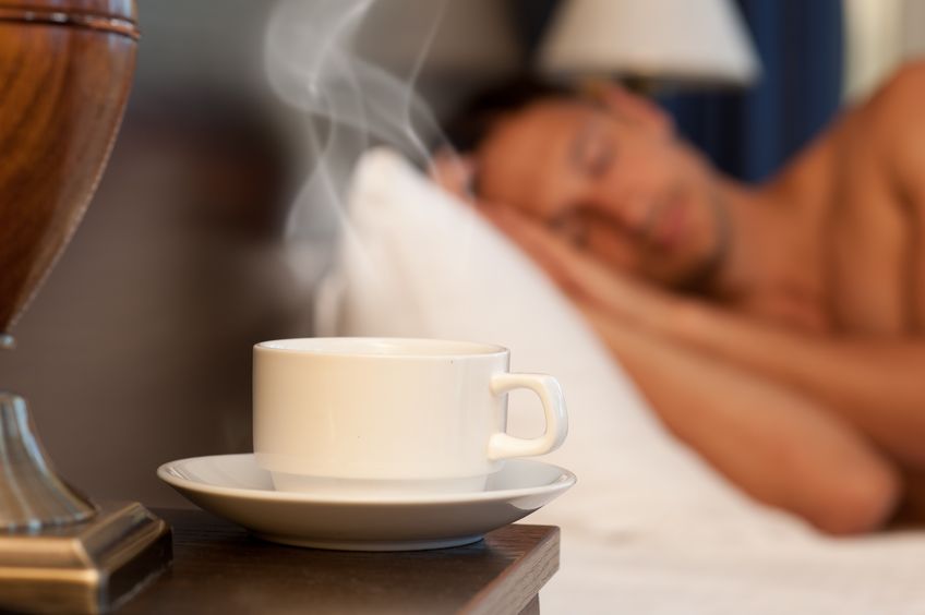 man sleeping in bed with tea beside him